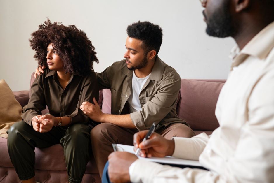 A man provides support to a sad woman during a therapy session with a psychiatrist, representing a couple seeking mental health care from a Cigna Insurance Psychiatrist in Sugar Land