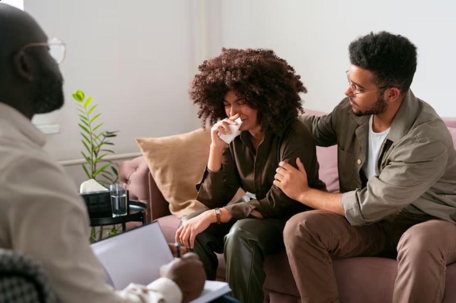 Woman crying during a counseling session while partner offers comfort, with therapist listening, illustrating compassionate bipolar treatment at Town Center Square