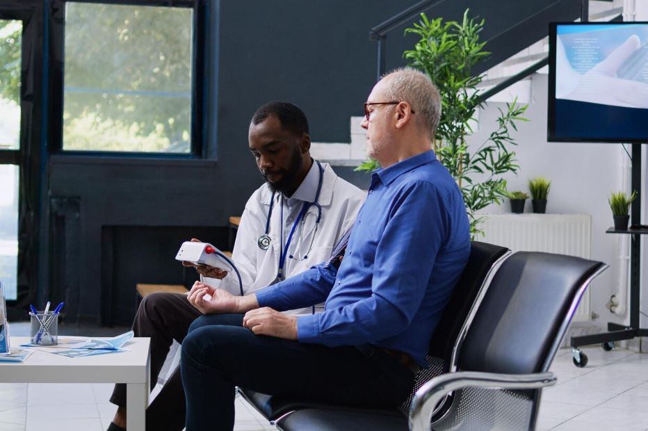 A patient receiving a health check from a Cigna Insurance Psychiatrist near Soldiers Field Court, using a medical device in a modern office with plants and a TV screen