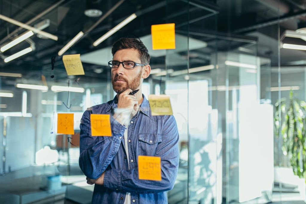Thoughtful man brainstorming with sticky notes in office, highlighting weekend ADHD