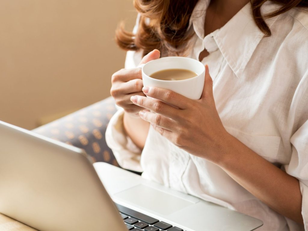 Woman sipping coffee at laptop, illustrating caffeine's potential benefits for ADHD focus – psychologist ADHD testing Sugar Land