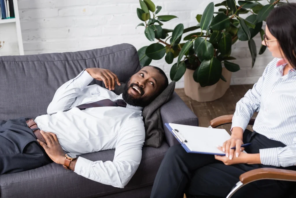 Relaxed patient on a couch with a United Healthcare psychiatrist in Sugar Land, in a serene office with plants, receiving compassionate therapy.