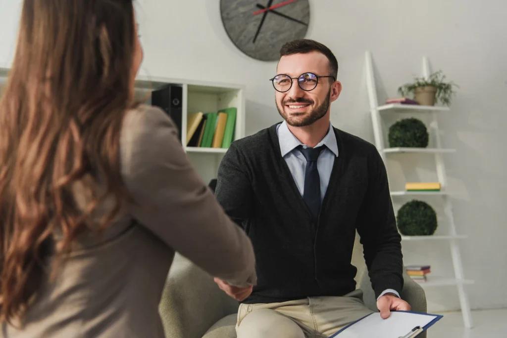 Professional handshake with a United Healthcare psychiatrist in Sugar Land, in a cozy office with bookshelves and clock for expert mental health care.