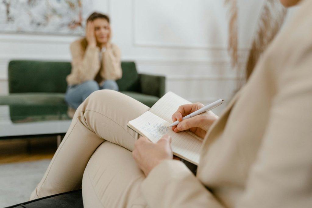 Counselor offering anxiety treatment support to a patient in Sugar Land, using a notebook in a tranquil office with soothing decor.