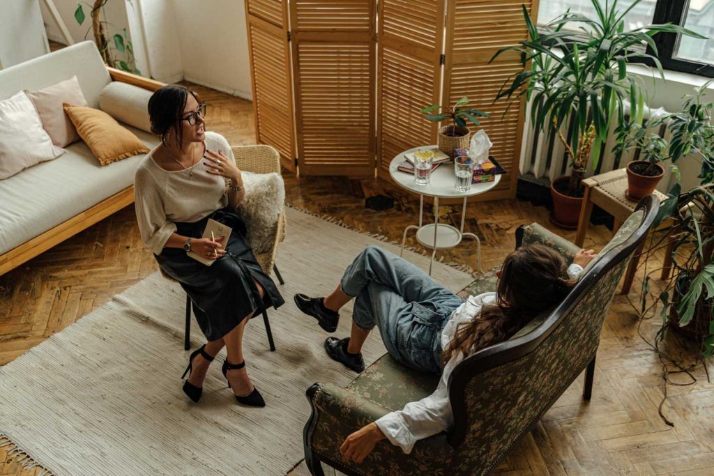 Therapist consulting a patient in a cozy ADHD psychiatrist office in Sugar Land, with plants and a notepad for support.