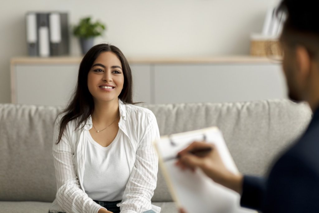 Anxiety Treatment Sugar Land support: woman speaks with therapist holding clipboard in organized, calming room.