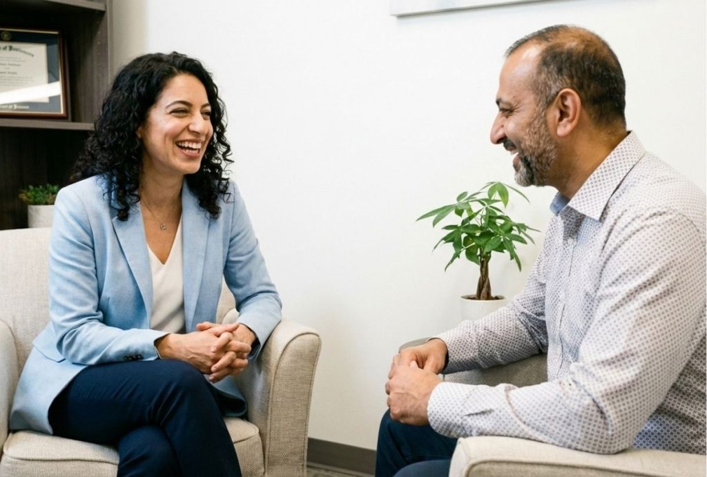 A friendly female Aetna psychiatrist in Sugar Land laughs with a male patient during a session.