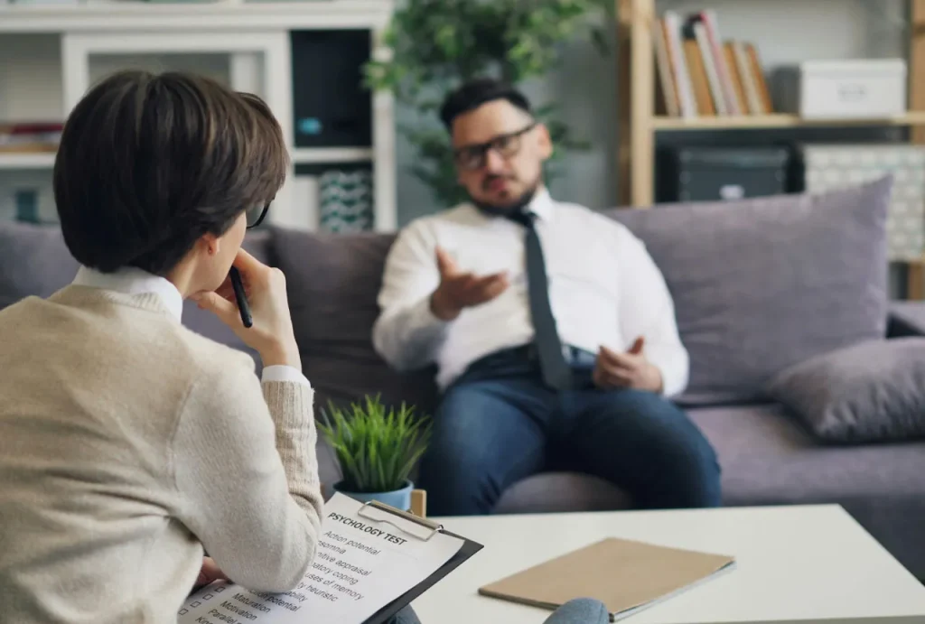 Over-the-shoulder shot of a therapist with bob haircut and clipboard, focusing on an anxiety treatment sugar land patient.