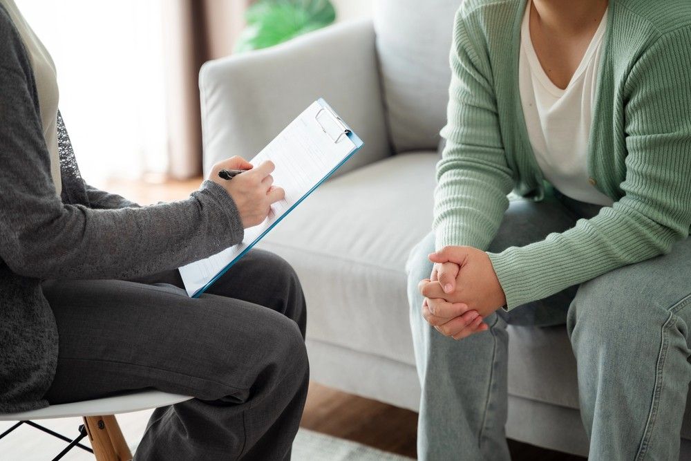 A Sugar Land psychiatrist taking notes during a therapy session with a patient. Find Blue Cross Blue Shield insurance options here.