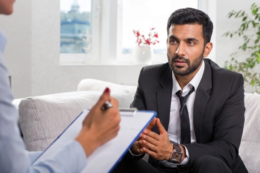 Anthem insurance psychiatrist in Sugar Land consults with a young businessman client who is listening intently.