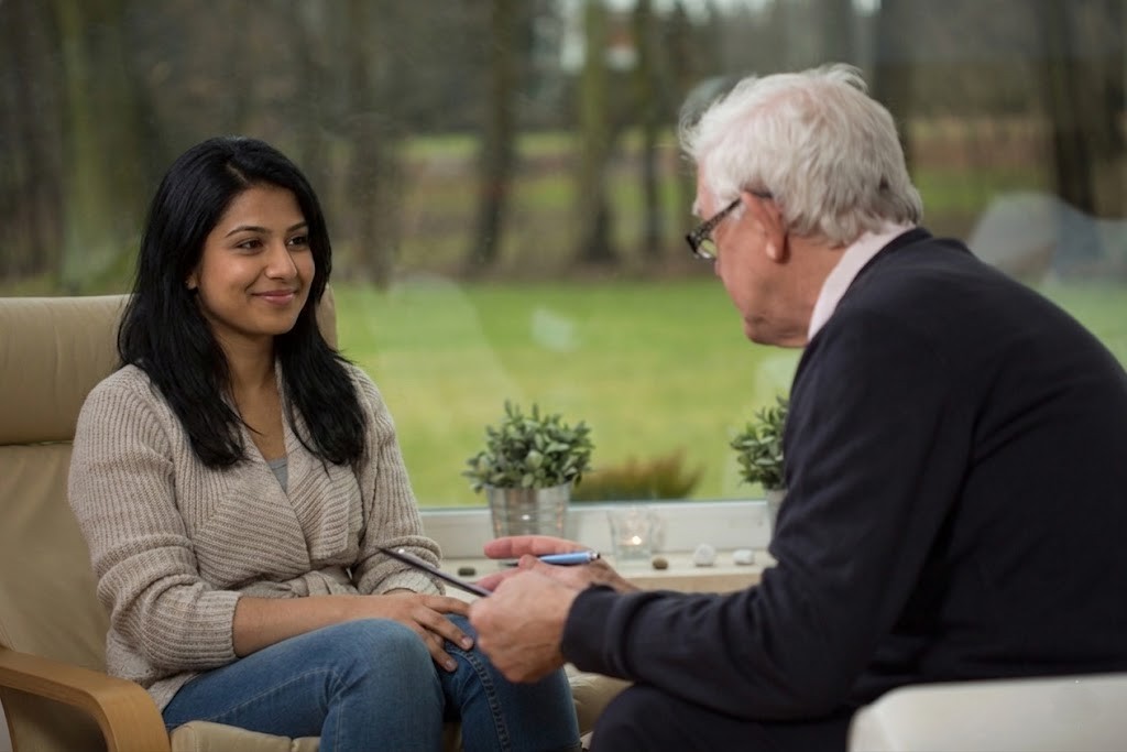 Young woman patient in beige sweater smiling at her experienced male therapist at anxiety doctors sugar land.