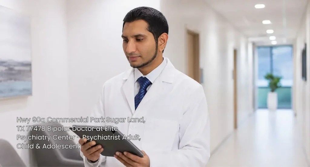 A professional bipolar doctor in Sugar Land holding a tablet in a modern medical clinic hallway at Elite Psychiatry. 